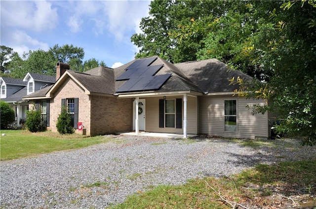 1613 Live Oak St, Slidell, LA 70460 - ranch-style home with roof mounted solar panels, brick siding, covered porch, a shingled roof, and a chimney