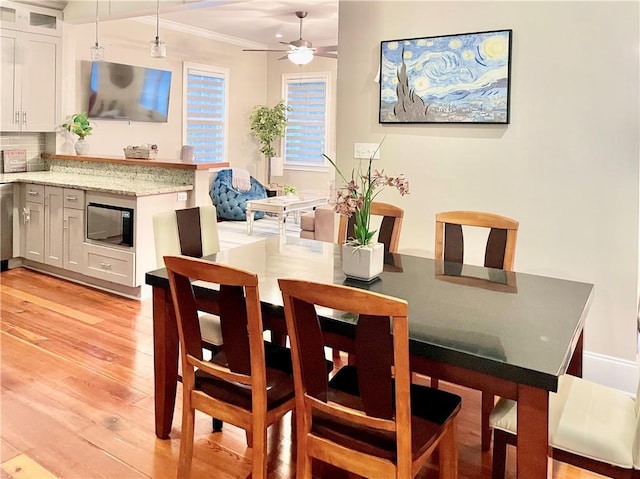 714 Third St, New Orleans, LA 70130 - dining area featuring light wood-type flooring, ornamental molding, and a ceiling fan