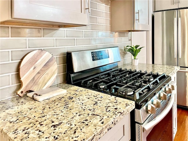 714 Third St, New Orleans, LA 70130 - kitchen with appliances with stainless steel finishes, backsplash, light stone countertops, and wood finished floors