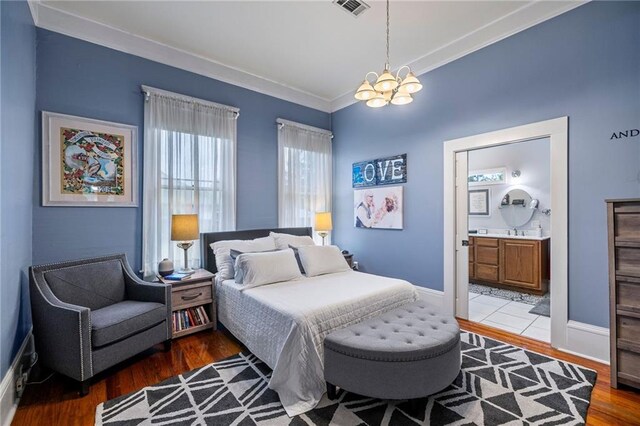 215 N 6th St, Ponchatoula, LA 70454 - bedroom with wood finished floors, a chandelier, ornamental molding, ensuite bath, and baseboards