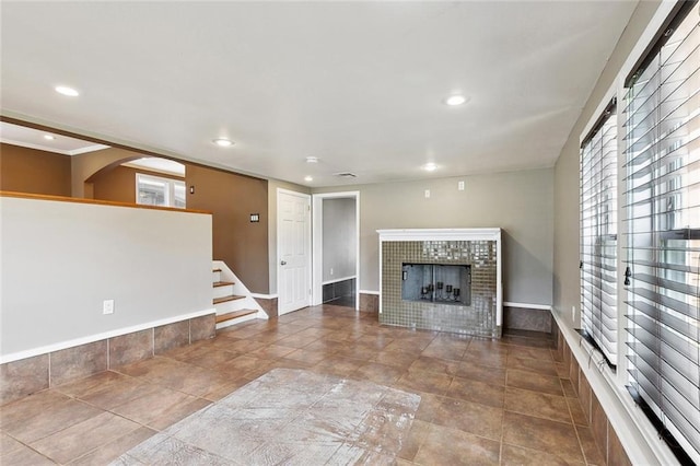 4959 Elysian Fields Ave, New Orleans, LA 70122 - unfurnished living room featuring a tiled fireplace, recessed lighting, baseboards, stairs, and plenty of natural light