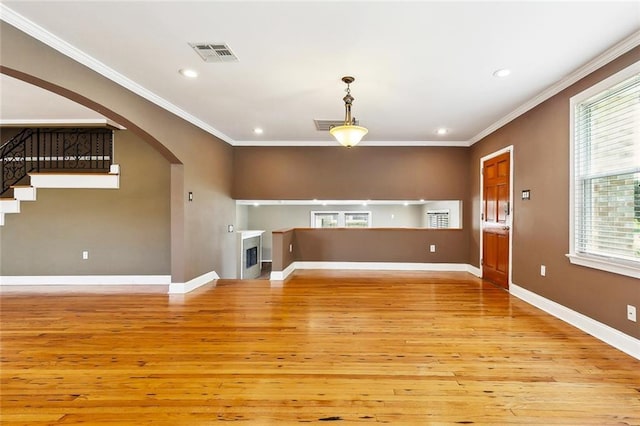 4959 Elysian Fields Ave, New Orleans, LA 70122 - unfurnished living room featuring light wood-style floors, crown molding, arched walkways, recessed lighting, and baseboards