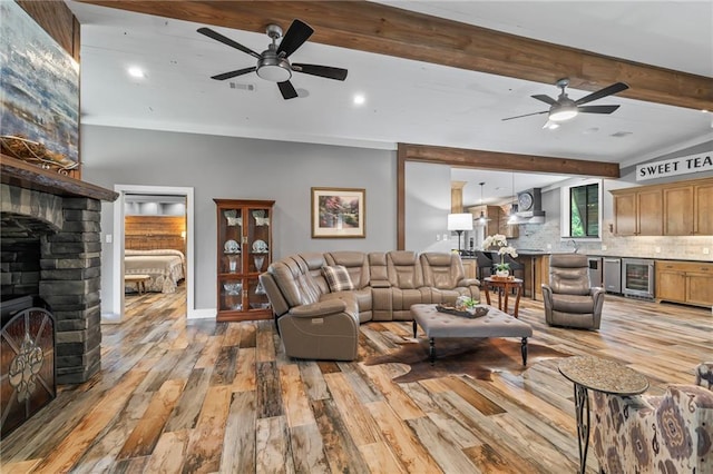 18064 Faller Rd, Tickfaw, LA 70466 - living room featuring ceiling fan, wine cooler, a fireplace, light wood-style floors, and beamed ceiling