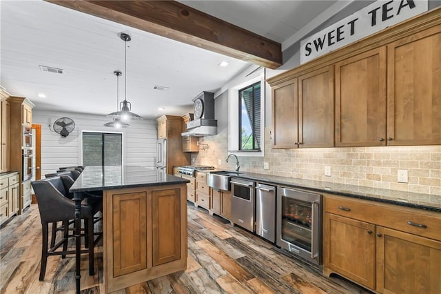 18064 Faller Rd, Tickfaw, LA 70466 - kitchen with beverage cooler, wood-type flooring, stainless steel appliances, wall chimney range hood, and a sink