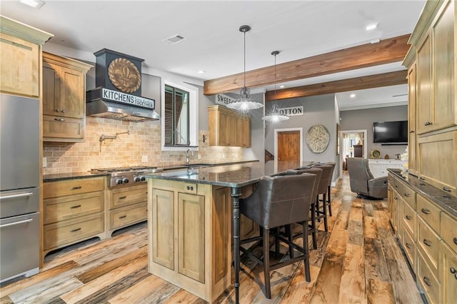 18064 Faller Rd, Tickfaw, LA 70466 - kitchen featuring appliances with stainless steel finishes, light wood-style floors, backsplash, a kitchen bar, and dark stone counters