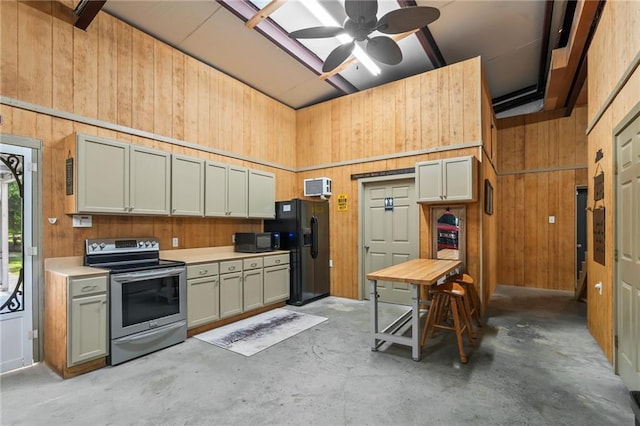18064 Faller Rd, Tickfaw, LA 70466 - kitchen with black appliances, wooden walls, light countertops, concrete flooring, and ceiling fan