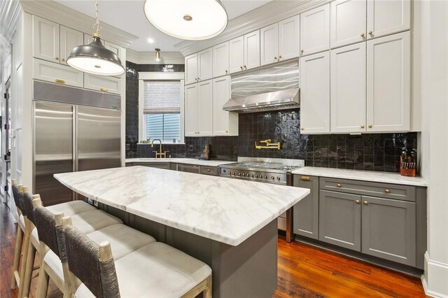 1026 Valence St, New Orleans, LA 70115 - kitchen with range hood, gray cabinetry, built in fridge, dark wood-style floors, and backsplash