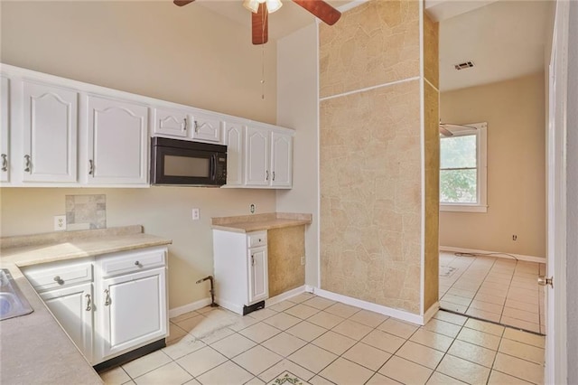 3337 Saint Ann St, New Orleans, LA 70119 - kitchen featuring black microwave, white cabinets, light tile patterned floors, and light countertops
