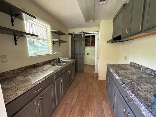 44373 Elmer Magee Rd, Franklinton, LA 70438 - kitchen featuring open shelves, a sink, a barn door, and light wood-style floors