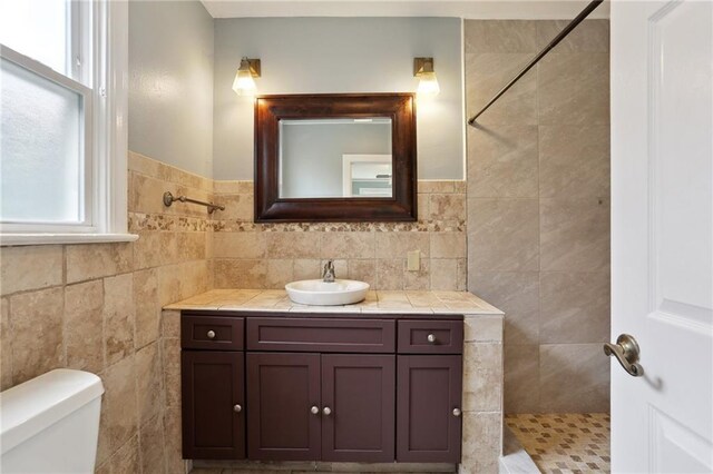 4435 Baccich St, New Orleans, LA 70122 - bathroom with a tile shower, vanity, toilet, and tile walls