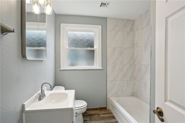 4435 Baccich St, New Orleans, LA 70122 - full bathroom with toilet, wood finish floors, vanity, and tub / shower combination