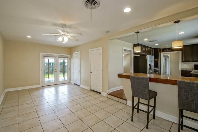3617 Tartan Dr, Metairie, LA 70003 - kitchen featuring stainless steel fridge, a ceiling fan, french doors, light tile patterned flooring, and a kitchen bar