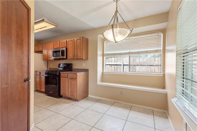 2577 Foliage Dr, Marrero, LA 70072 - kitchen with black range with gas stovetop, stainless steel microwave, light tile patterned floors, decorative light fixtures, and baseboards