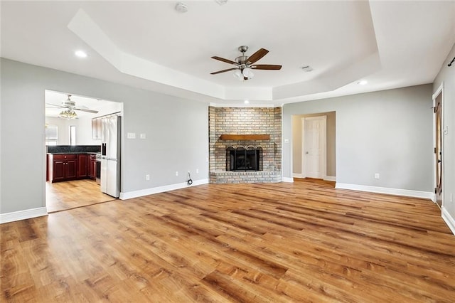 2716 Mayflower St, Meraux, LA 70075 - unfurnished living room with a ceiling fan, a raised ceiling, recessed lighting, light wood-style floors, and a brick fireplace