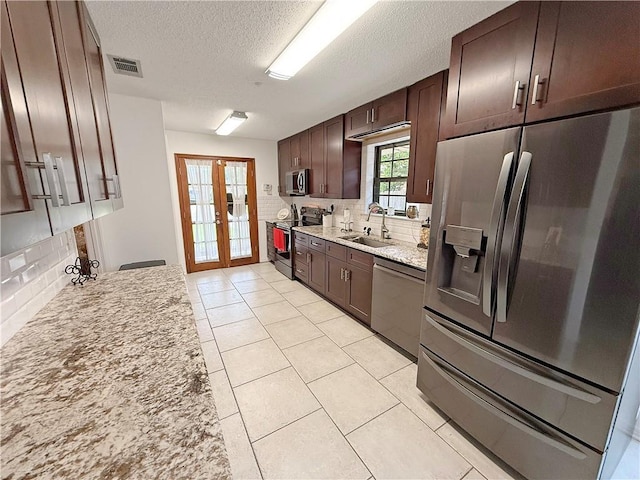 8809 Belle Grove Pl, River Ridge, LA 70123 - kitchen featuring stainless steel appliances, a sink, decorative backsplash, a textured ceiling, and dark brown cabinets