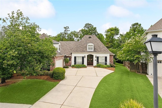 404 Southdown Loop, Covington, LA 70433 - french country inspired facade with driveway, brick siding, an attached garage, a shingled roof, and french doors