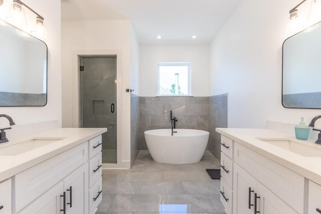 322 Spartan Loop, Slidell, LA 70458 - bathroom featuring a shower stall, two vanities, marble look tiles, a soaking tub, and tile walls
