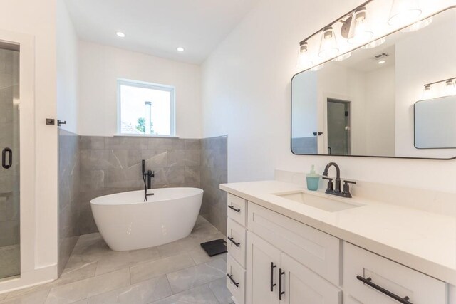 322 Spartan Loop, Slidell, LA 70458 - bathroom featuring vanity, a stall shower, a freestanding bath, tile walls, and wainscoting