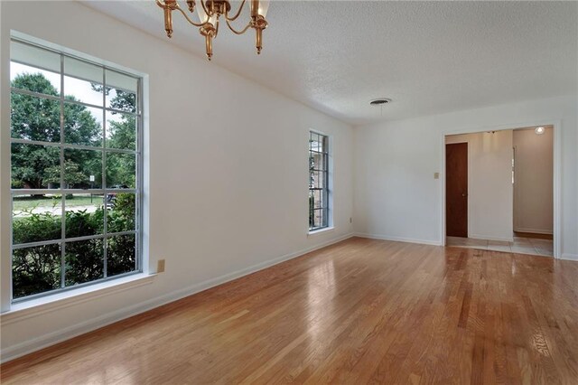 1569 Maplewood Dr, Slidell, LA 70458 - unfurnished room with a textured ceiling, a chandelier, light wood finished floors, healthy amount of natural light, and baseboards
