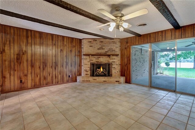 1569 Maplewood Dr, Slidell, LA 70458 - unfurnished living room featuring a textured ceiling, a ceiling fan, beamed ceiling, wood walls, and a brick fireplace