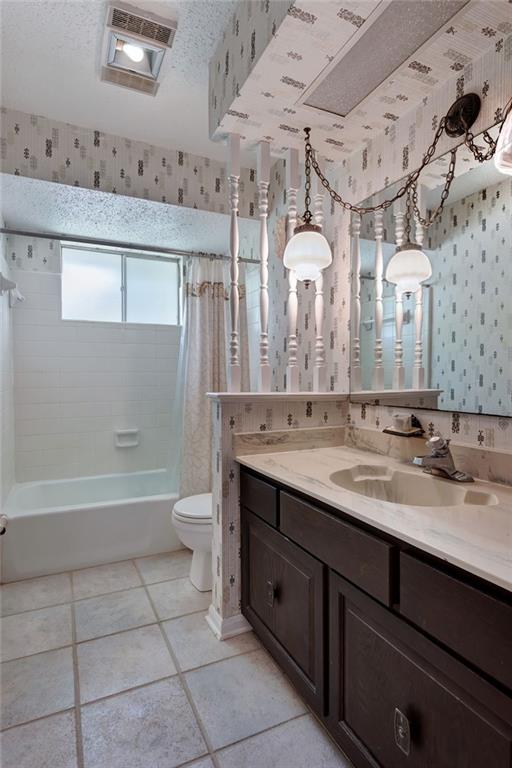 1569 Maplewood Dr, Slidell, LA 70458 - bathroom with wallpapered walls, vanity, toilet, tile patterned flooring, and shower / tub combo