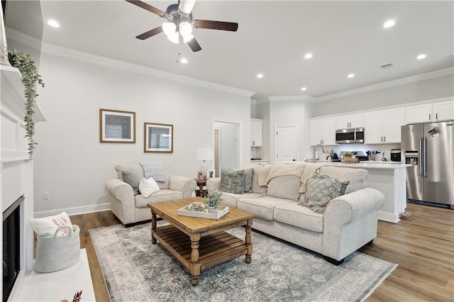 39651 Fairhope Dr, Ponchatoula, LA 70454 - living area featuring light wood finished floors, a ceiling fan, ornamental molding, recessed lighting, and a fireplace