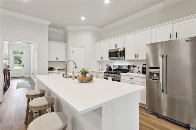 39651 Fairhope Dr, Ponchatoula, LA 70454 - kitchen with stainless steel appliances, crown molding, an island with sink, light wood-style flooring, and light countertops