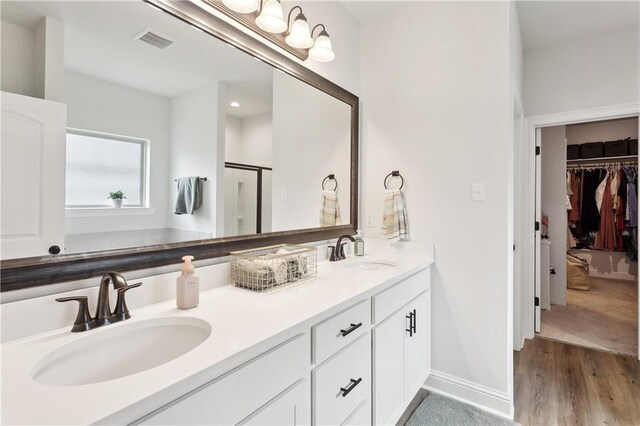 39651 Fairhope Dr, Ponchatoula, LA 70454 - bathroom featuring double vanity, a stall shower, a walk in closet, wood finished floors, and recessed lighting