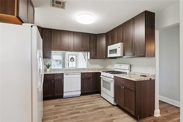 2409 Corinne Dr, Chalmette, LA 70043 - kitchen with white appliances, light wood-style flooring, dark brown cabinetry, baseboards, and light stone counters