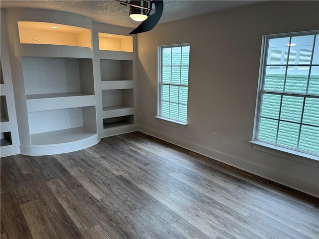 1005 David Dr, Metairie, LA 70003 - unfurnished living room with built in features, healthy amount of natural light, a textured ceiling, and dark wood-style floors