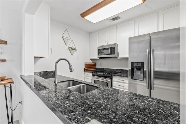 120 W Pineridge St Unit 120, Mandeville, LA 70448 - kitchen with appliances with stainless steel finishes, dark stone counters, white cabinetry, and a peninsula