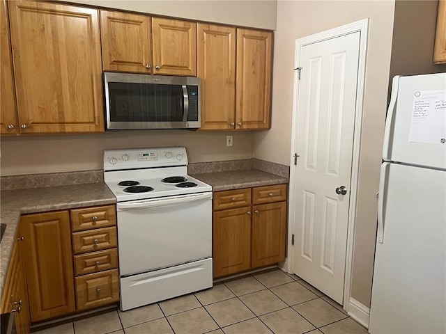 4441 Burbank Dr Unit 308, Baton Rouge, LA 70820 - kitchen with white appliances, brown cabinetry, light tile patterned flooring, and dark countertops