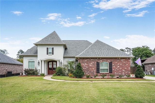 1067 Scarlet Oak Ln, Mandeville, LA 70448 - french country home with roof with shingles, a front yard, stucco siding, and brick siding