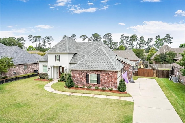 1067 Scarlet Oak Ln, Mandeville, LA 70448 - french country style house with a shingled roof, driveway, brick siding, central air condition unit, and stucco siding
