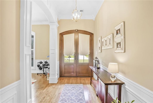 1067 Scarlet Oak Ln, Mandeville, LA 70448 - entrance foyer featuring arched walkways, crown molding, a wainscoted wall, light wood finished floors, and french doors