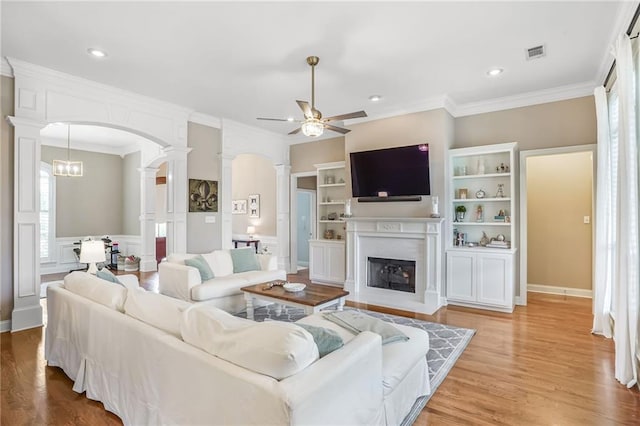 1067 Scarlet Oak Ln, Mandeville, LA 70448 - living room with decorative columns, arched walkways, ceiling fan, ornamental molding, and a fireplace with flush hearth