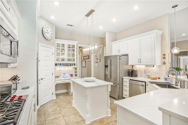 1067 Scarlet Oak Ln, Mandeville, LA 70448 - kitchen featuring appliances with stainless steel finishes, decorative backsplash, a sink, a center island, and white cabinetry