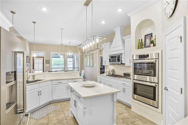 1067 Scarlet Oak Ln, Mandeville, LA 70448 - kitchen featuring appliances with stainless steel finishes, a sink, a kitchen island, light countertops, and light tile patterned floors