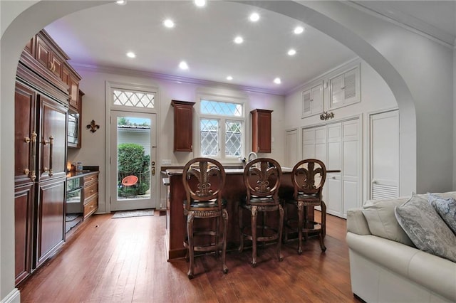 5936 Chestnut St, New Orleans, LA 70115 - kitchen featuring ornamental molding, arched walkways, dark wood-style floors, a breakfast bar area, and open floor plan