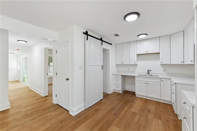 35210 Windsor Dr, Slidell, LA 70460 - kitchen with a sink, a barn door, light wood finished floors, and white cabinets