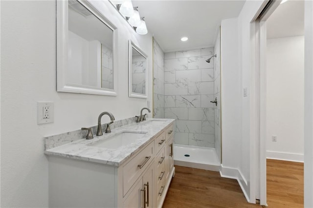 35210 Windsor Dr, Slidell, LA 70460 - bathroom with double vanity, a tile shower, wood finished floors, and baseboards