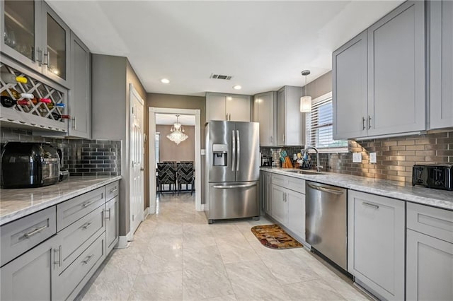 3816 Jean Lafitte Pkwy, Chalmette, LA 70043 - kitchen with stainless steel appliances, gray cabinetry, a sink, backsplash, and light stone counters