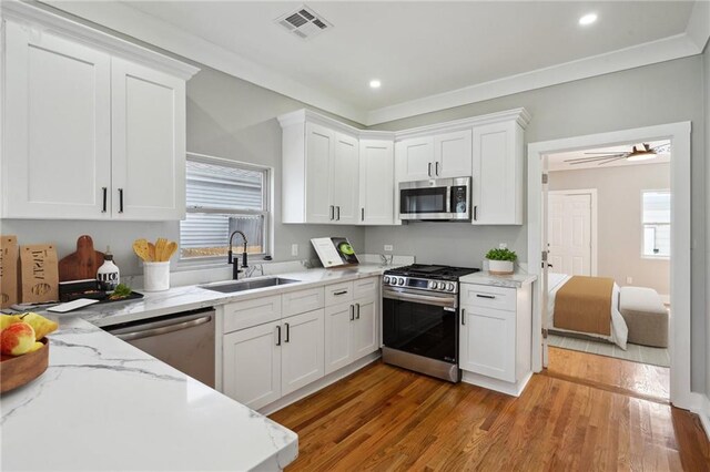 2327 Pauline St, New Orleans, LA 70117 - kitchen with appliances with stainless steel finishes, white cabinetry, light wood-type flooring, light stone counters, and recessed lighting