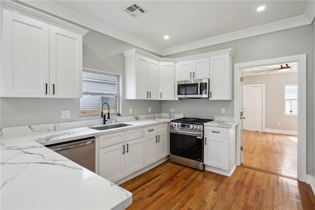 2327 Pauline St, New Orleans, LA 70117 - kitchen featuring stainless steel appliances, a sink, white cabinets, light wood-style flooring, and recessed lighting