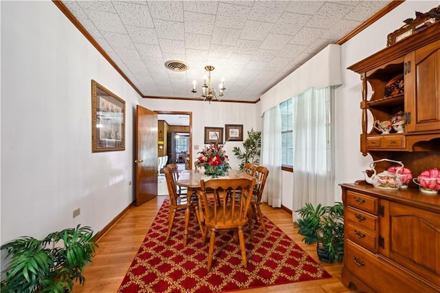 2108 Washington St, Franklinton, LA 70438 - dining area with ornamental molding, light wood-type flooring, a chandelier, plenty of natural light, and baseboards