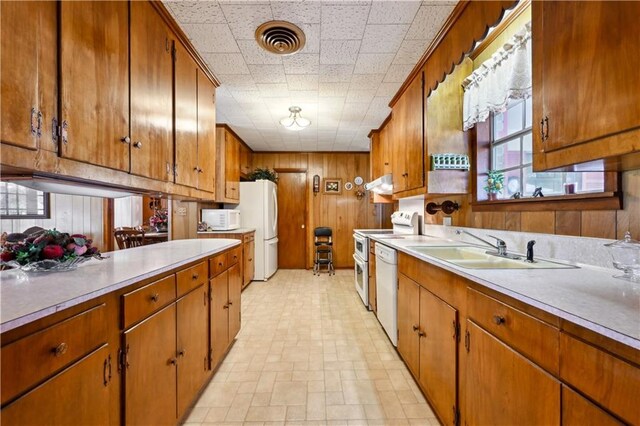2108 Washington St, Franklinton, LA 70438 - kitchen featuring a sink, under cabinet range hood, white appliances, light countertops, and wood walls