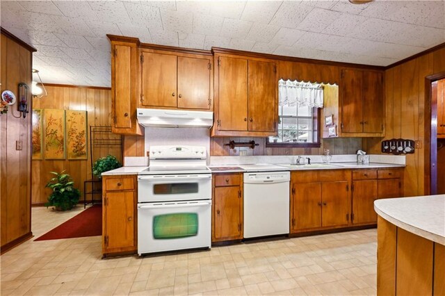 2108 Washington St, Franklinton, LA 70438 - kitchen featuring white appliances, under cabinet range hood, wooden walls, light countertops, and brown cabinetry