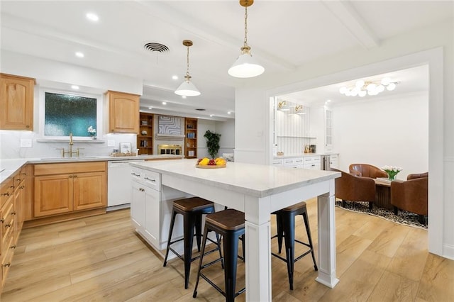 4905 Haring Ct, Metairie, LA 70006 - kitchen featuring white dishwasher, a sink, a breakfast bar area, beam ceiling, and light wood-type flooring