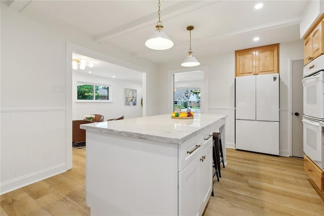 4905 Haring Ct, Metairie, LA 70006 - kitchen with white appliances, light wood-style floors, a center island, beam ceiling, and light stone counters