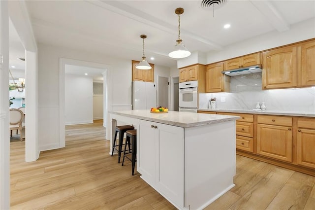 4905 Haring Ct, Metairie, LA 70006 - kitchen featuring oven, beamed ceiling, decorative backsplash, light wood-style floors, and under cabinet range hood